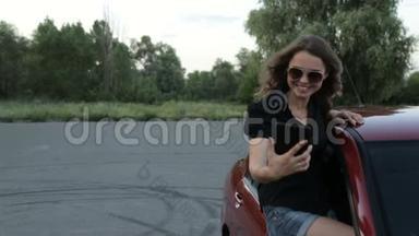 一个女孩在红色的汽车背景上用平板电脑拍照